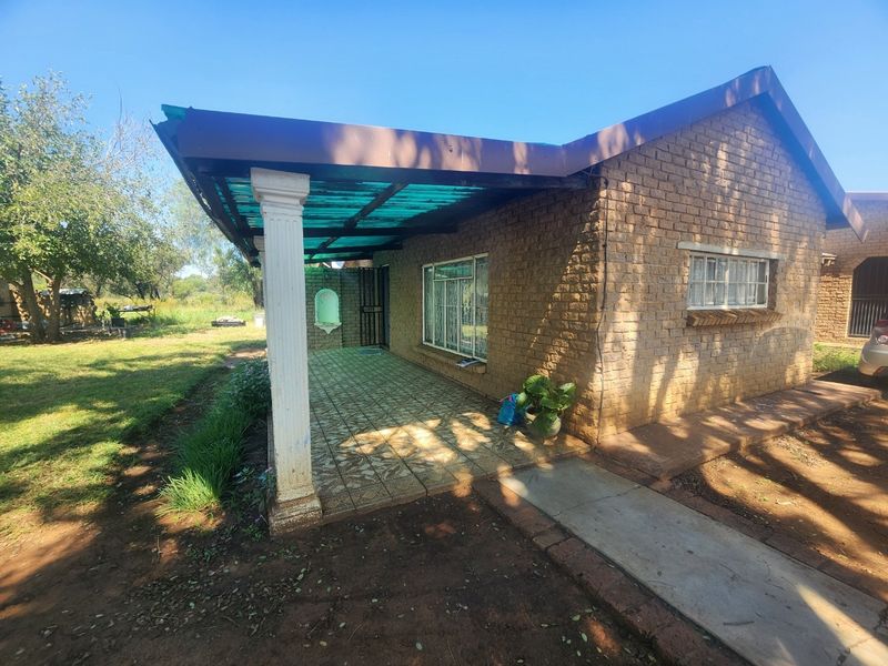 A covered patio area featuring brick exterior walls, tiled flooring, a decorative column, and a translucent roof, providing a functional outdoor space.