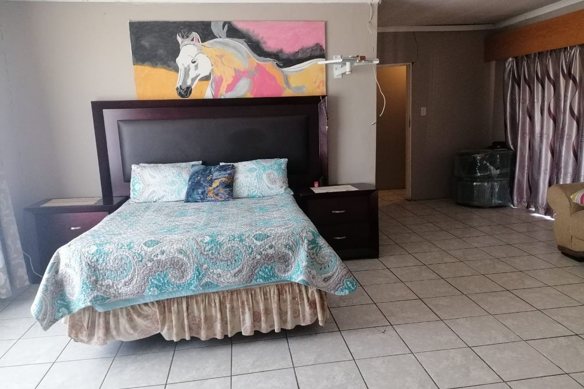 Spacious bedroom featuring tiled flooring and neutral wall tones, offering a blank canvas for potential interior updates and modernization.