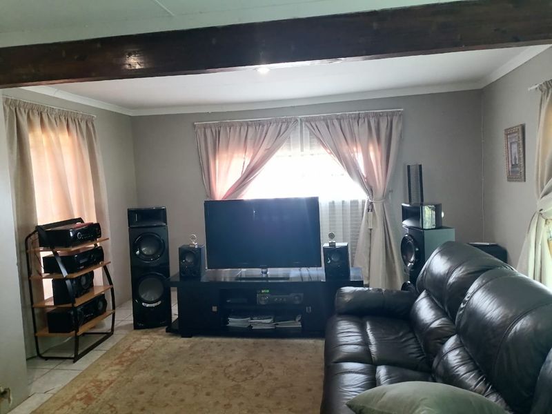 A comfortable living room featuring an exposed timber ceiling beam and tiled flooring, providing a functional space for relaxation and entertainment.