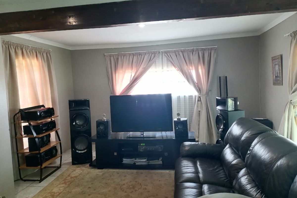 A comfortable living room featuring an exposed timber ceiling beam and tiled flooring, providing a functional space for relaxation and entertainment.