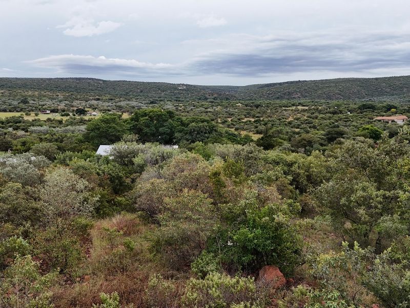 A scenic elevated view of the surrounding natural landscape, featuring dense native vegetation and rolling hills.