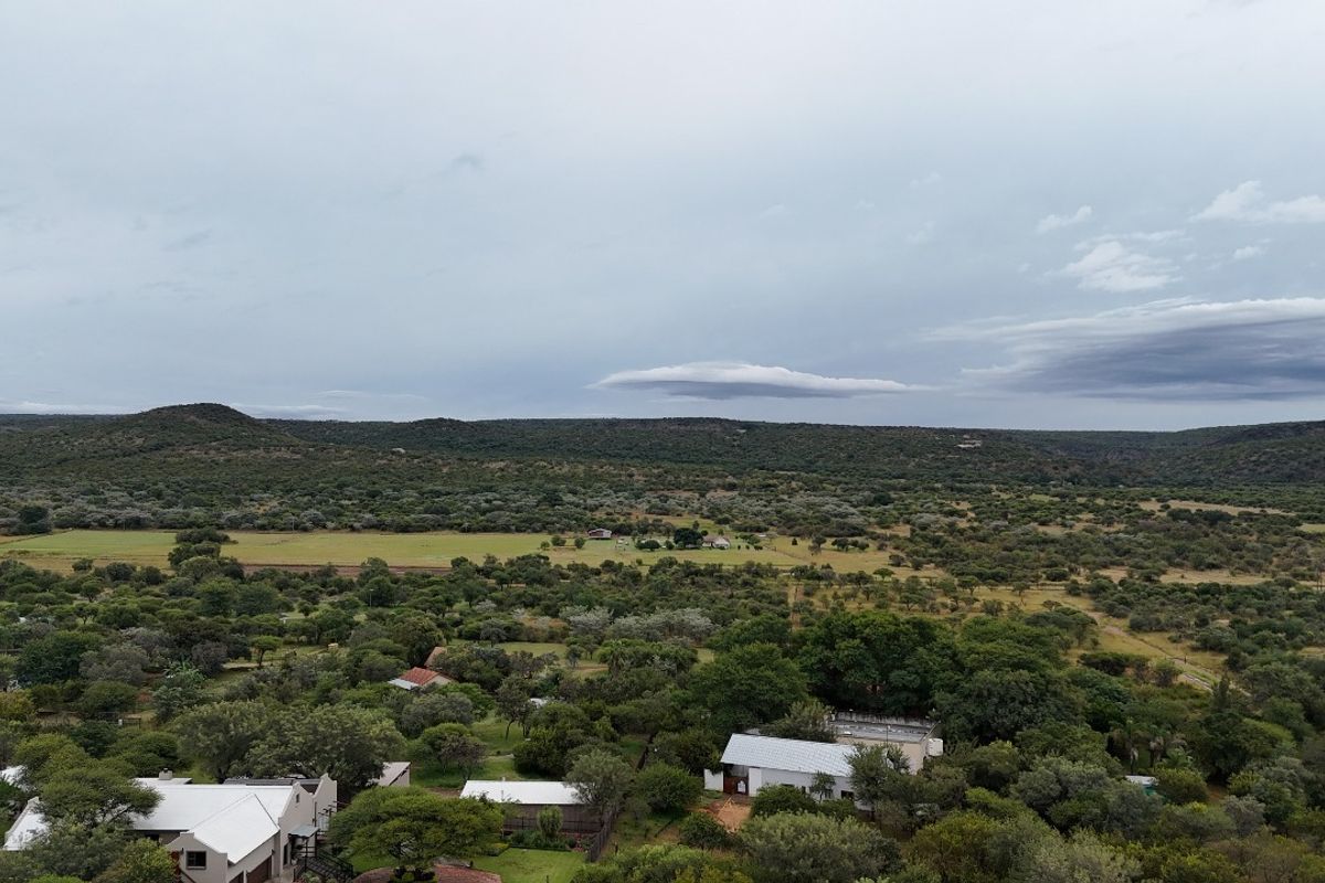 An aerial view of the residential vacant land property, showcasing the surrounding landscape, natural vegetation, and nearby structures.