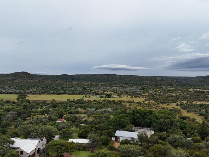 An aerial view of the residential vacant land property, showcasing the surrounding landscape, natural vegetation, and nearby structures.