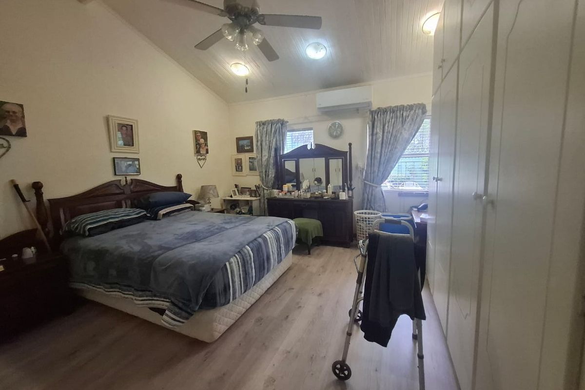 Spacious bedroom featuring vaulted ceilings, built-in cupboards, laminate flooring, and a split-system air conditioner for climate control.