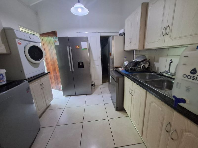 A functional kitchen featuring built-in cabinetry, double bowl sink, and tiled flooring, providing a practical workspace for daily culinary and utility tasks.
