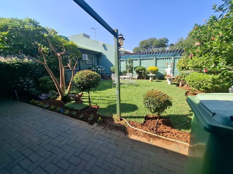A well-maintained rear garden featuring a paved patio area, manicured lawn, and secure perimeter fencing.