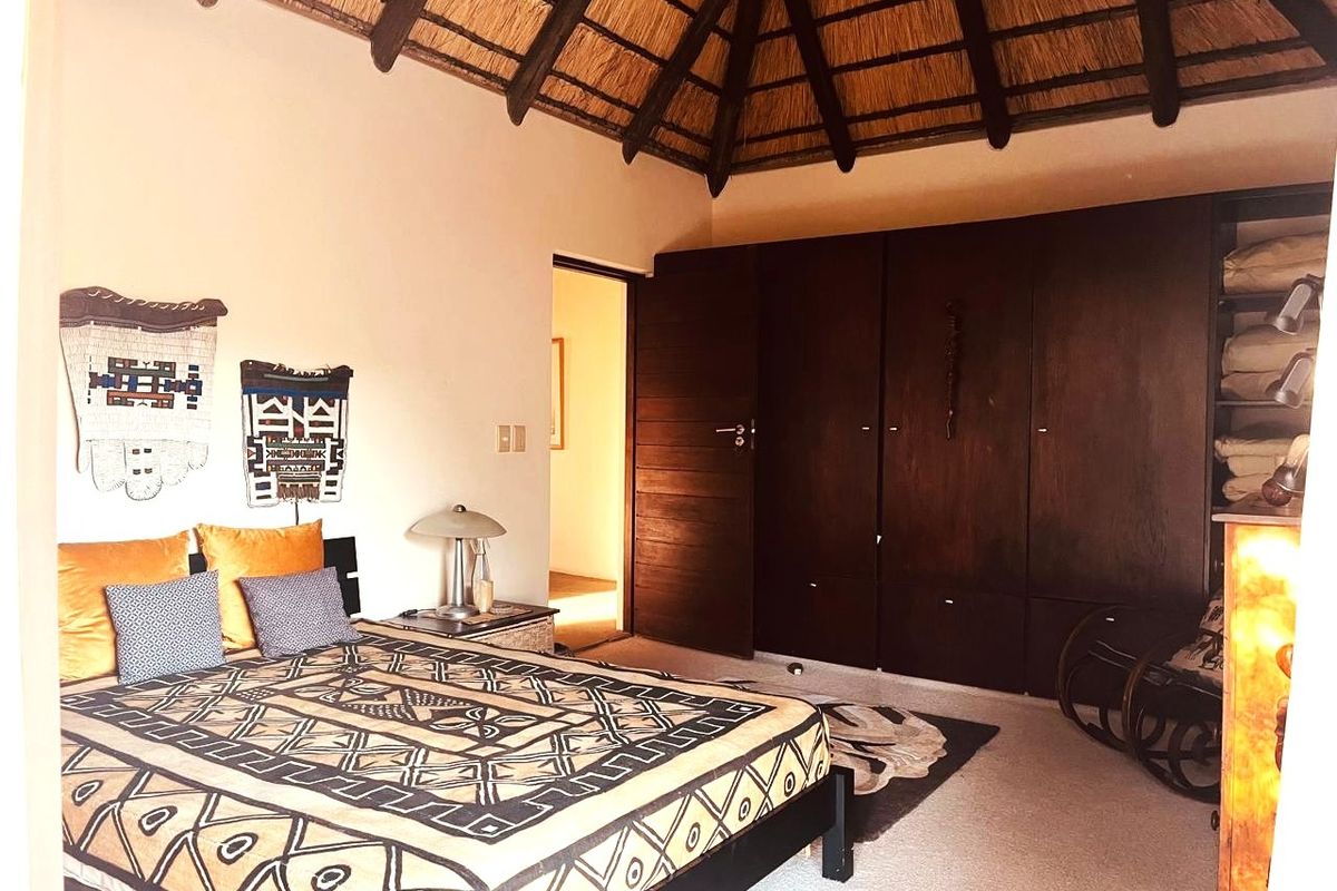Spacious bedroom featuring a high vaulted thatched ceiling with exposed timber rafters and extensive built-in wooden cabinetry.