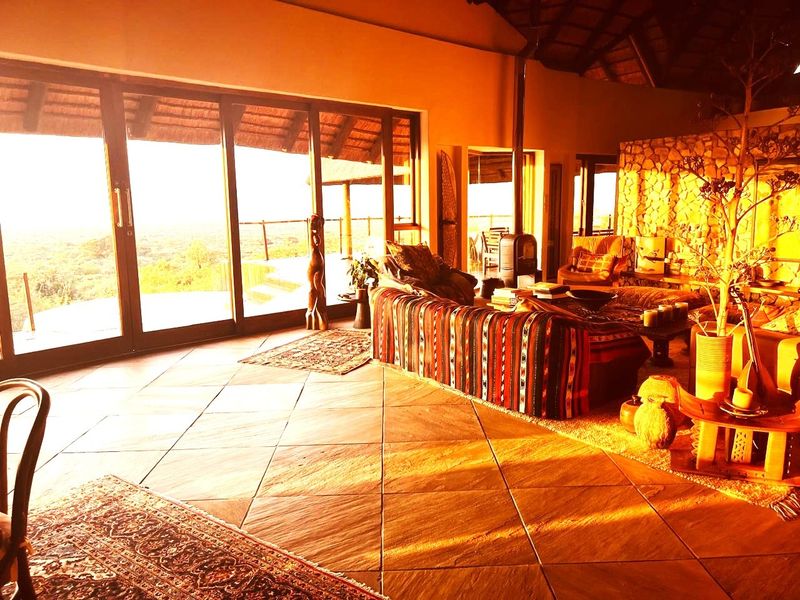 Spacious living area featuring a stone accent wall, tiled floors, and large sliding doors that open to an expansive outdoor view.