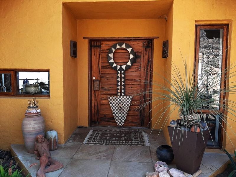 A welcoming entrance featuring a unique timber front door, stone tiled flooring, and warm-toned exterior walls with integrated lighting.