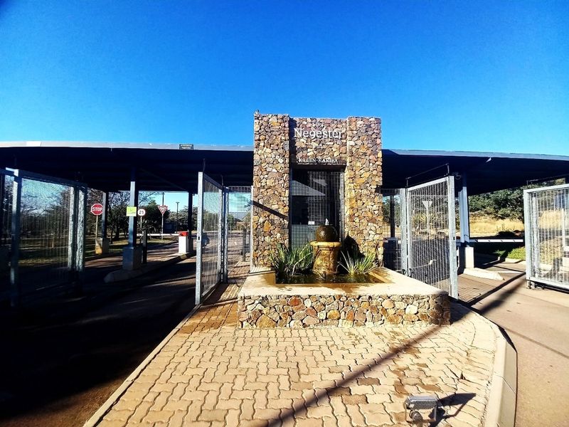 The main entrance gatehouse of the residential estate, featuring stone cladding, a central water feature, and secure boom gate access.