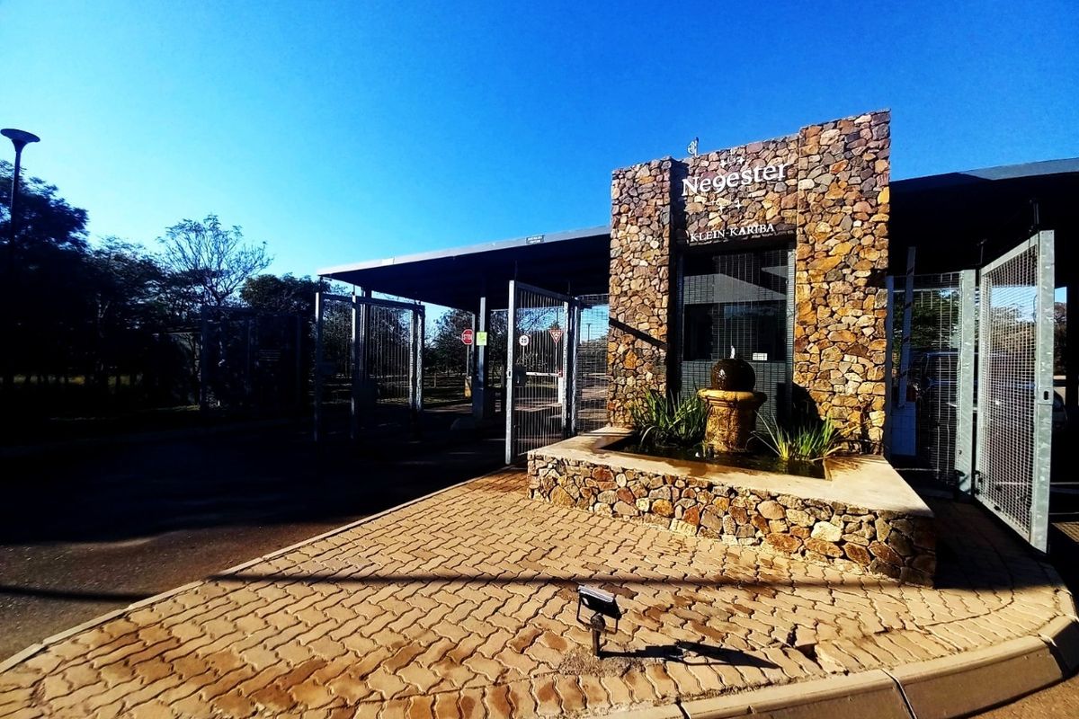The entrance gate to the Negester Klein Kariba estate, featuring stone-clad pillars, a decorative water feature, and secure access control.