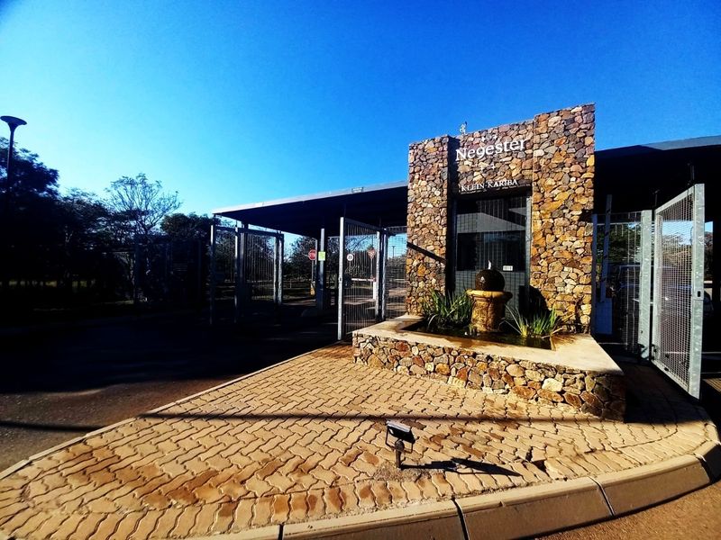 The entrance gate to the Negester Klein Kariba estate, featuring stone-clad pillars, a decorative water feature, and secure access control.