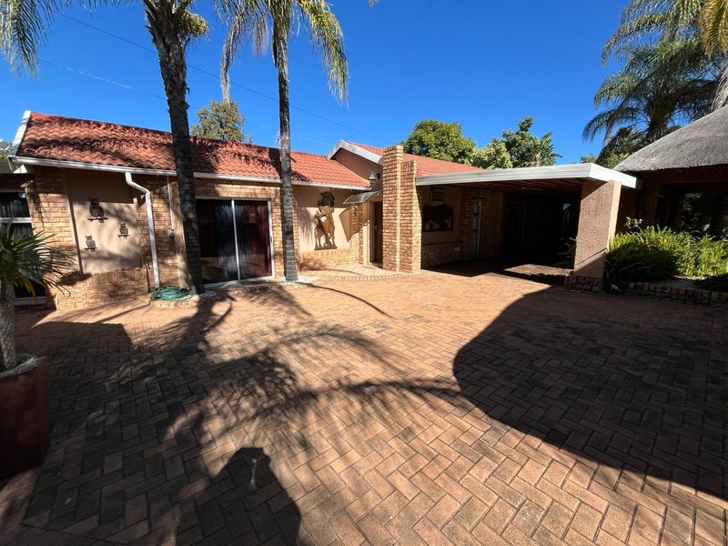 Front exterior view of the house featuring a brick paved driveway, covered carport, and tiled roof architecture.
