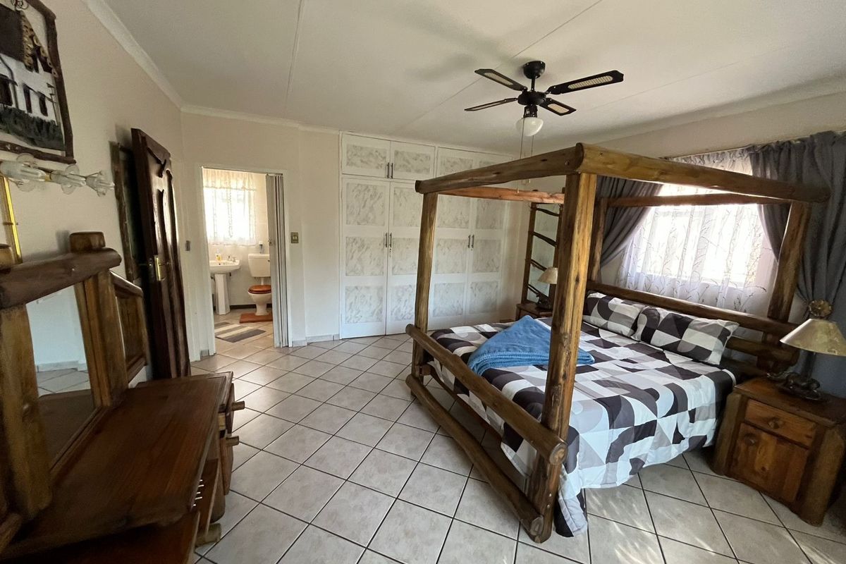 Spacious bedroom featuring tiled flooring, built-in cupboards, and an en-suite bathroom access.