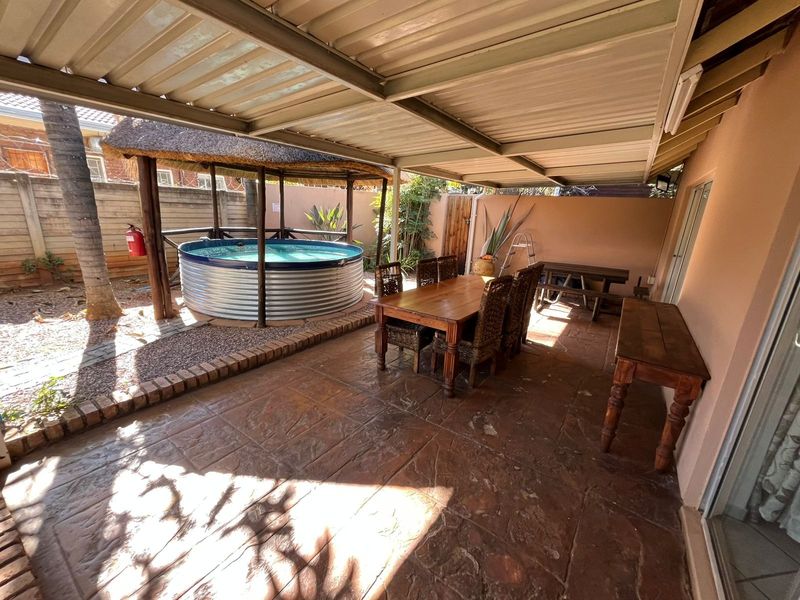 Covered patio area featuring stamped concrete flooring, a built-in above-ground plunge pool with a thatch gazebo, and direct access to the main dwelling.