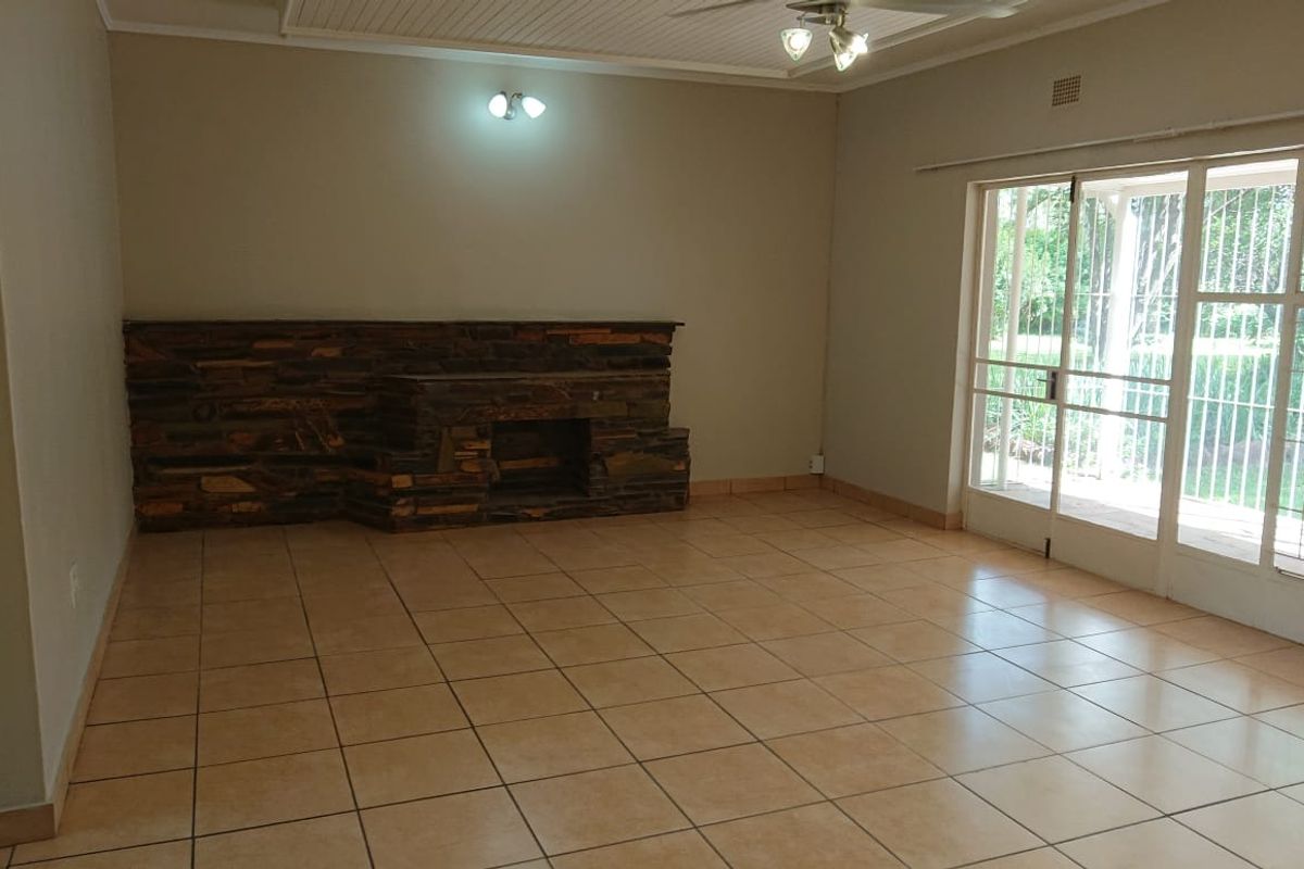 Spacious living room featuring a prominent stone fireplace, ceramic tiled flooring, and large sliding glass doors providing access to the outdoor area.