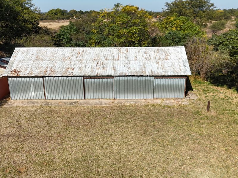 Aerial view of a large corrugated iron outbuilding or shed with a concrete apron, situated on a rural small holding property.