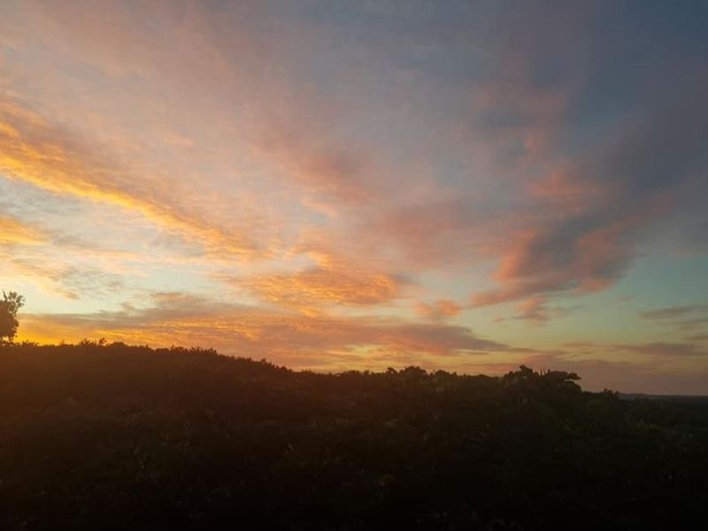 A scenic view of the horizon at sunset, showcasing the natural landscape and sky over the vacant residential land.