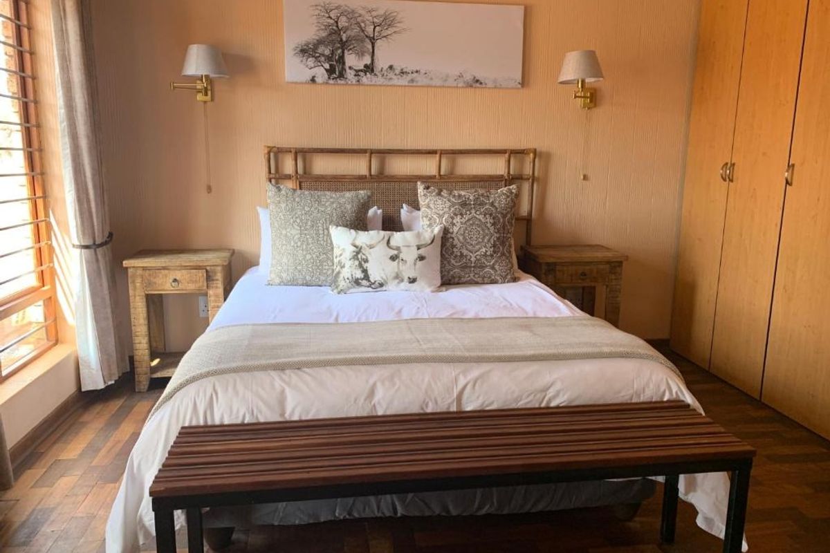 A cozy bedroom featuring warm-toned walls, classic parquet flooring, and ample built-in wardrobe storage, creating a comfortable and inviting sleeping space.