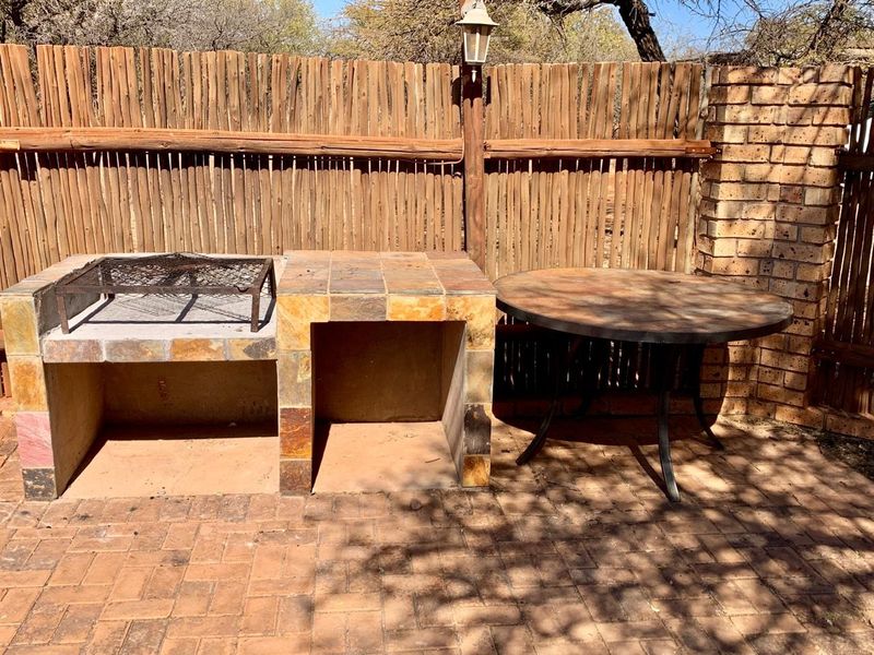 Outdoor patio area featuring a built-in tiled braai station, brick paving, and timber screen fencing, providing a functional space for outdoor cooking and entertaining.