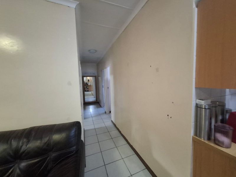 A narrow hallway featuring tiled flooring and neutral wall finishes, providing access to other areas of the townhouse.