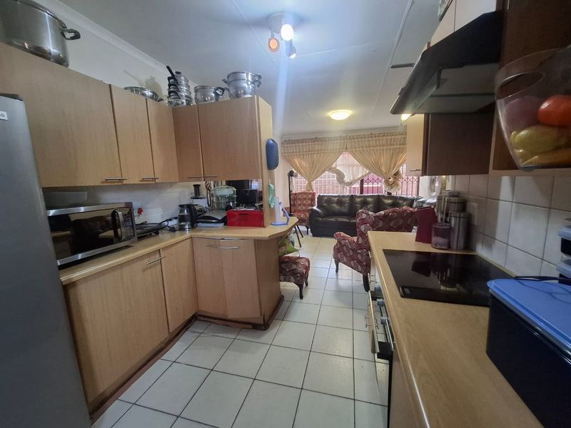 Open-plan kitchen and living area featuring laminate cabinetry, tiled flooring, and integrated cooking appliances, creating a functional and connected living space.