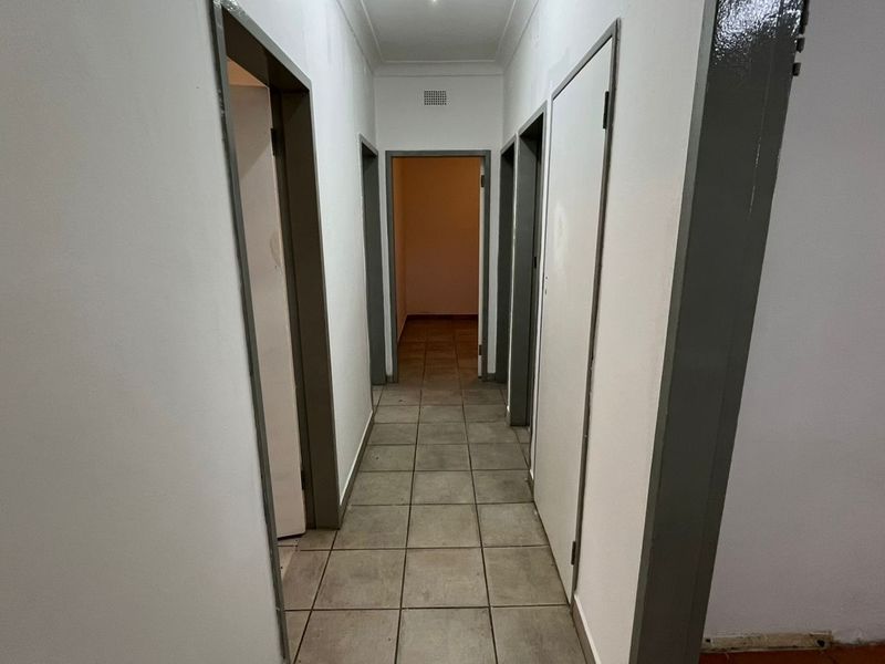 A functional, empty hallway featuring tiled flooring and multiple doorways leading to various rooms within the home.