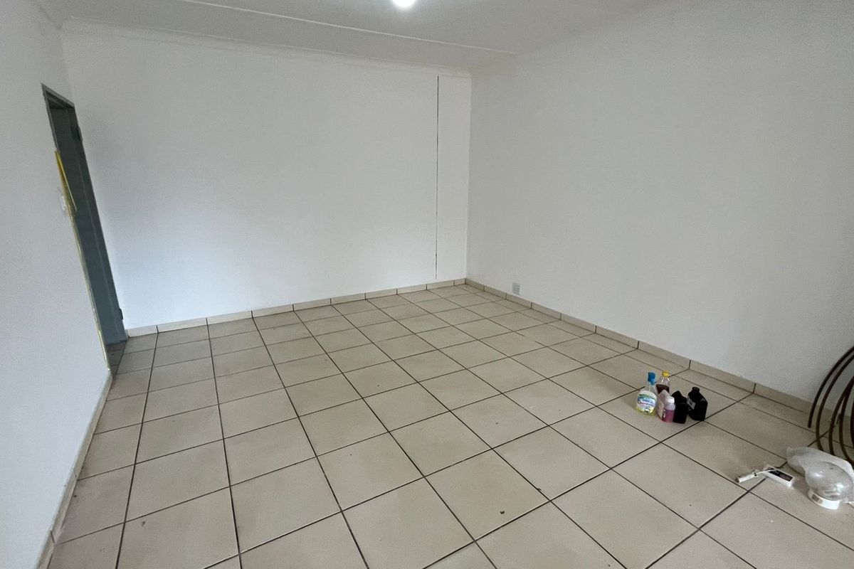 An empty, neutral living area featuring ceramic floor tiles and clean white walls, providing a blank canvas for interior design.