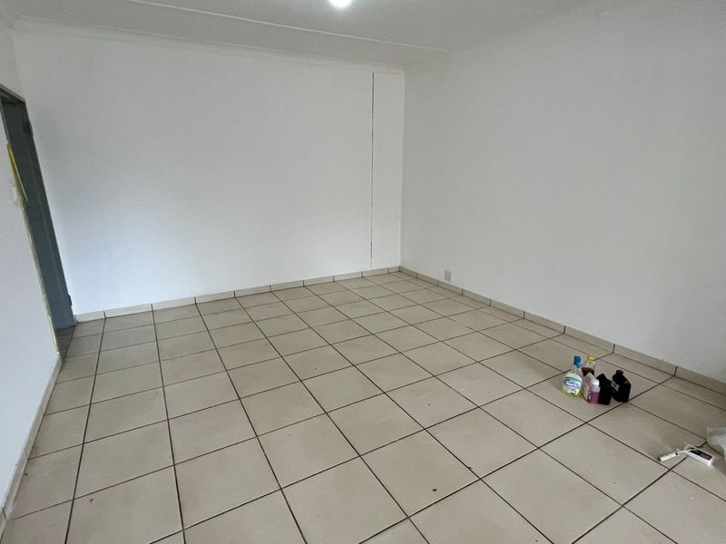 An empty, neutral living area featuring ceramic floor tiles and clean white walls, providing a blank canvas for interior design.