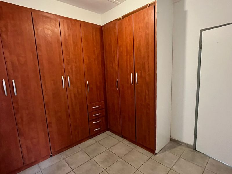 A bedroom featuring extensive built-in wooden cabinetry and neutral tiled flooring, offering ample storage space.