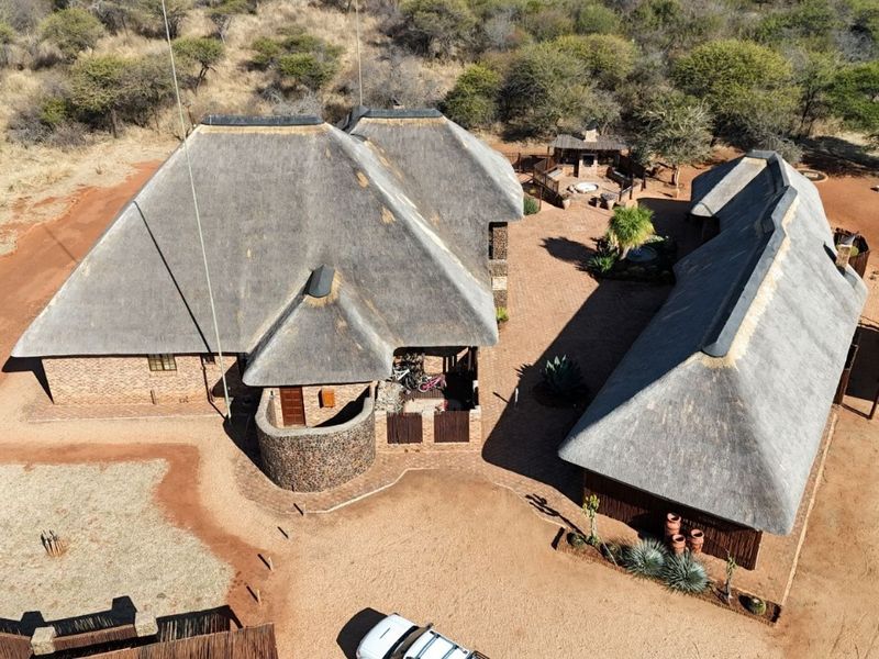Aerial view of a bushveld property featuring multiple structures with traditional thatch roofing, brick construction, and a central paved courtyard area.