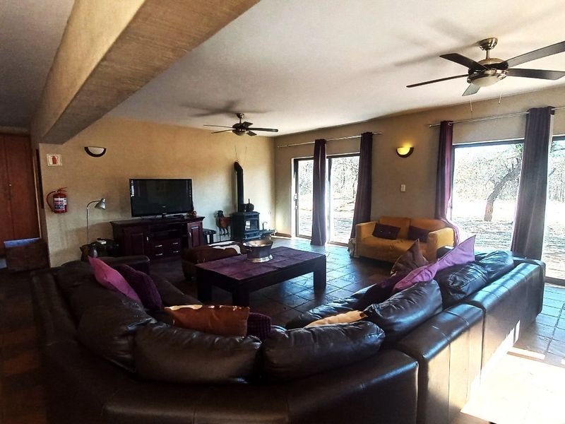 Spacious living room featuring tiled flooring, a wood-burning stove, ceiling fans, and large sliding glass doors providing access to the outdoor area.