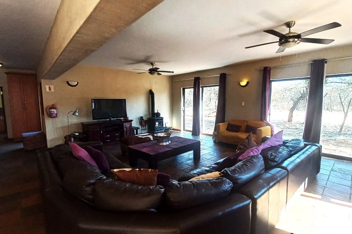 Spacious living room featuring tiled flooring, a wood-burning stove, ceiling fans, and large sliding glass doors providing access to the outdoor area.