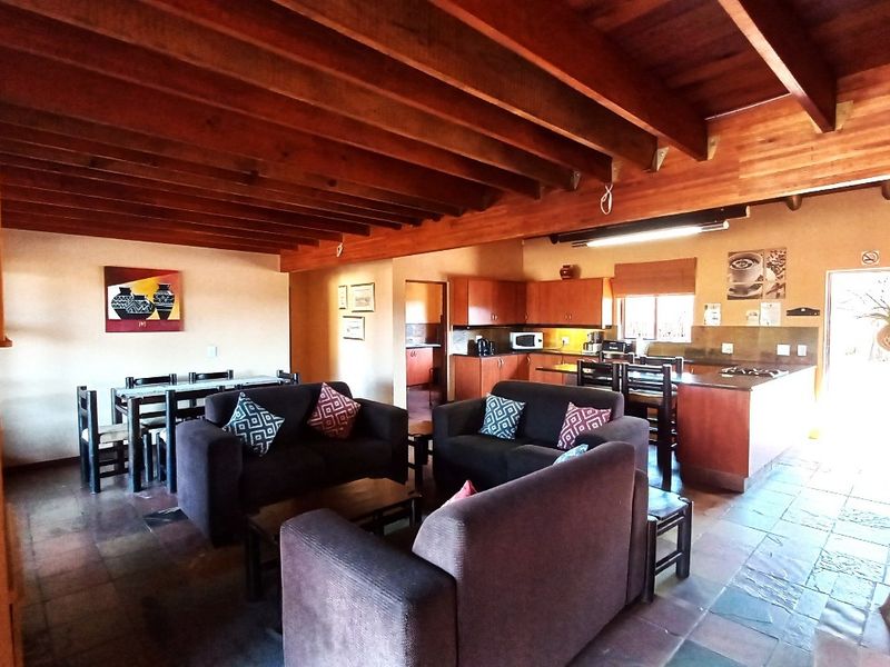 Spacious open-plan living and kitchen area featuring exposed timber beam ceilings, slate tile flooring, and a functional kitchen layout with a central island.