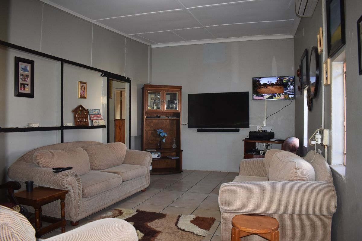 A functional living room featuring tiled flooring, a coved ceiling, and a wall-mounted air conditioning unit.