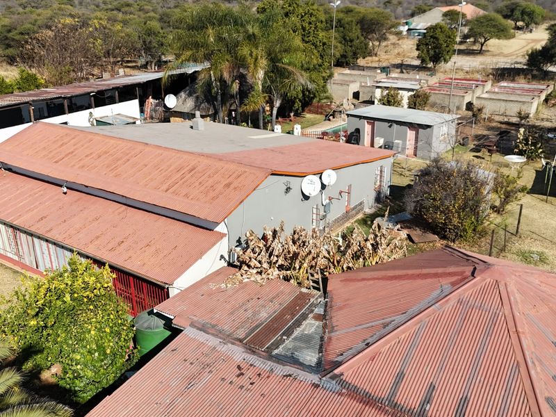 Aerial view of the small holding property showing multiple outbuildings, corrugated metal roofing, and surrounding grounds.