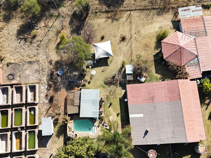 Aerial view of the small holding property featuring multiple outbuildings, a swimming pool, and various concrete troughs set within a large rural plot.