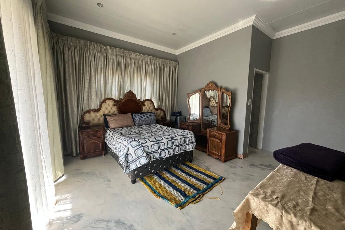 Spacious bedroom featuring marble-effect flooring, decorative coving, and recessed downlighting, offering a neutral backdrop for personal styling.
