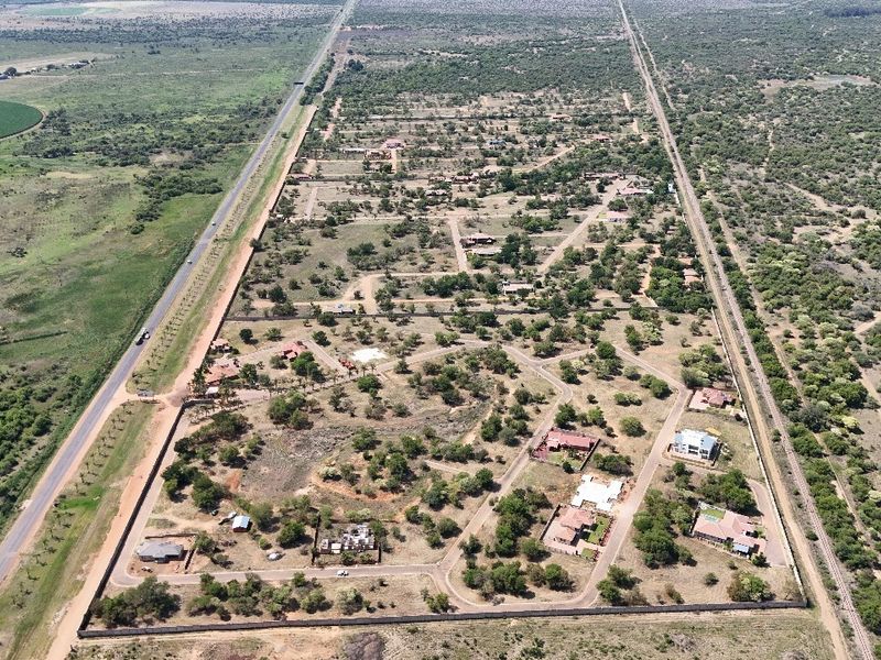 An aerial view of a residential estate development featuring established plots, internal road networks, and perimeter security fencing.
