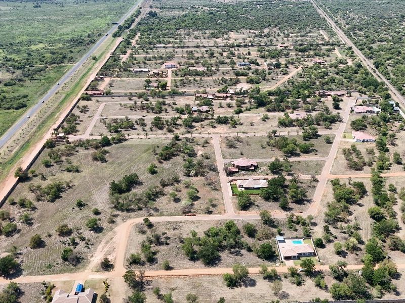 An aerial view of a residential estate development featuring established plots, internal road networks, and perimeter security fencing.
