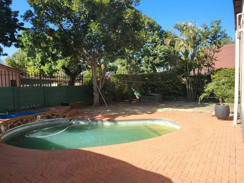Outdoor pool area featuring a swimming pool with brick paved surround and boundary walling.