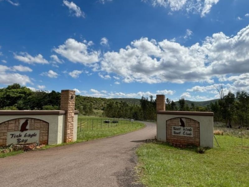 Entrance gate to Fish Eagle Bay featuring stone masonry pillars and paved driveway access into the residential estate.
