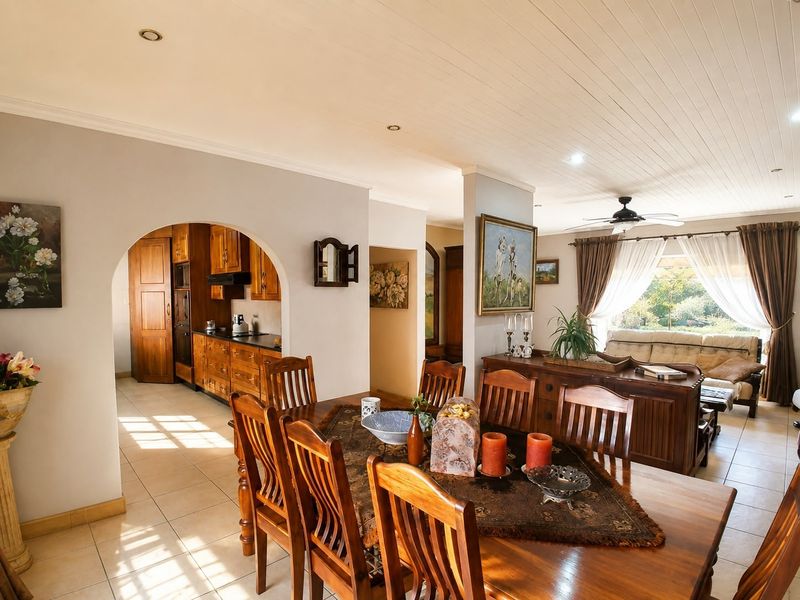 Open-plan dining and kitchen area featuring timber cabinetry, tiled flooring, and a classic archway connecting the living space.