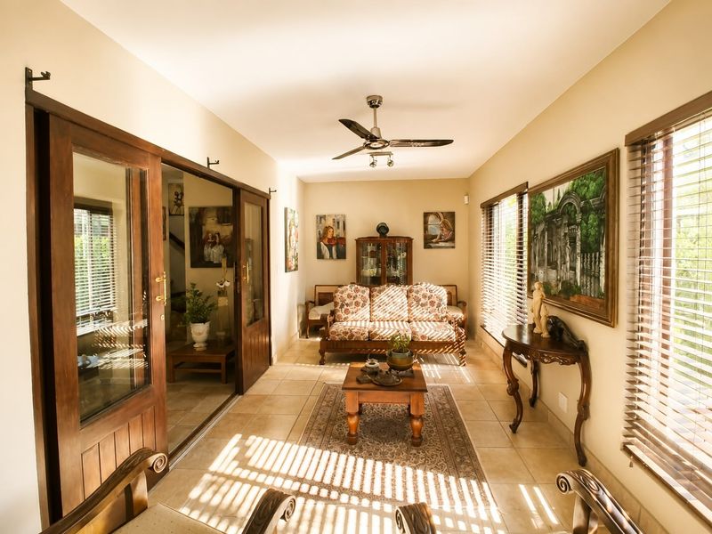A bright living room featuring tiled flooring, a ceiling fan, and large sliding glass doors that provide ample natural light.