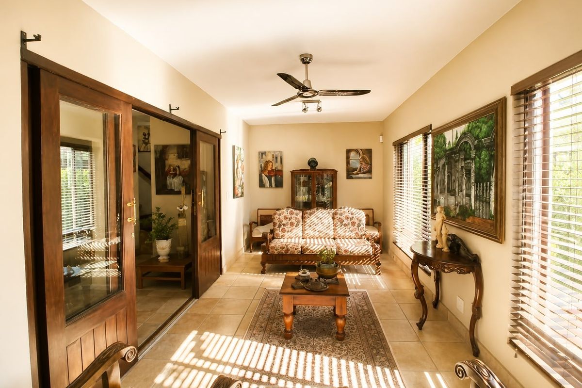 A bright living room featuring tiled flooring, a ceiling fan, and large sliding glass doors that provide ample natural light.