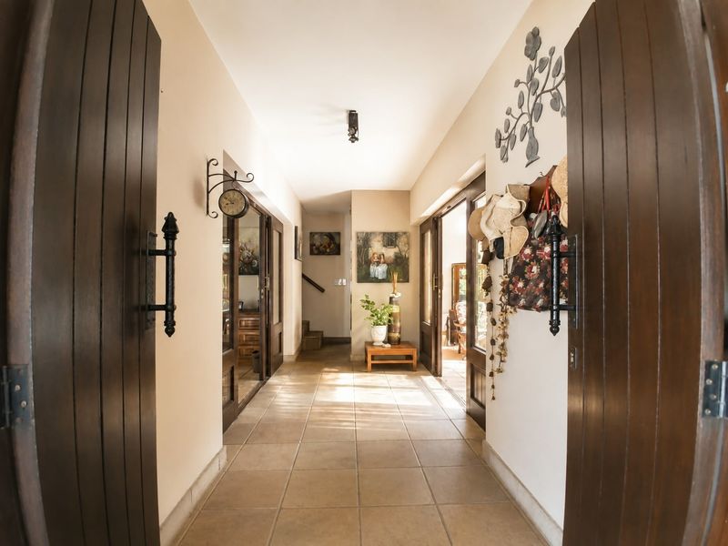 A welcoming entrance hallway featuring tiled flooring and double timber doors, providing a bright and spacious transition area within the home.
