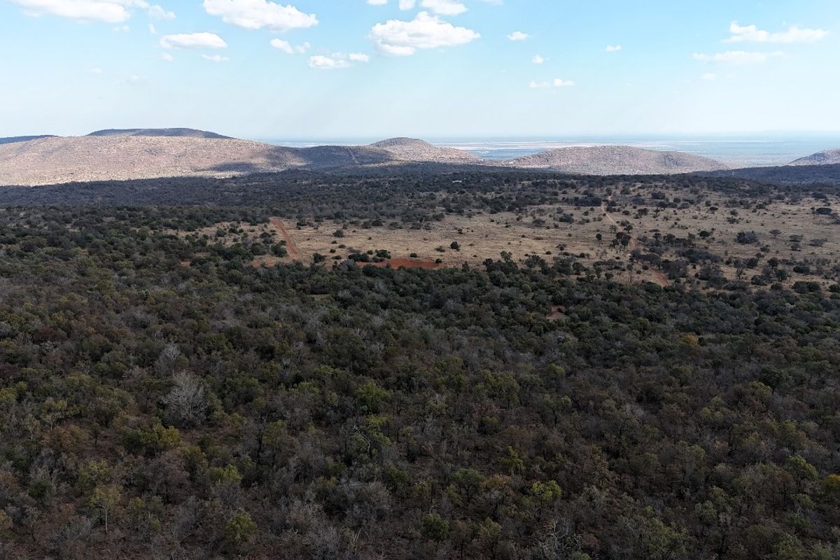 An aerial view of expansive vacant residential land featuring native bushveld vegetation and distant mountain range vistas.