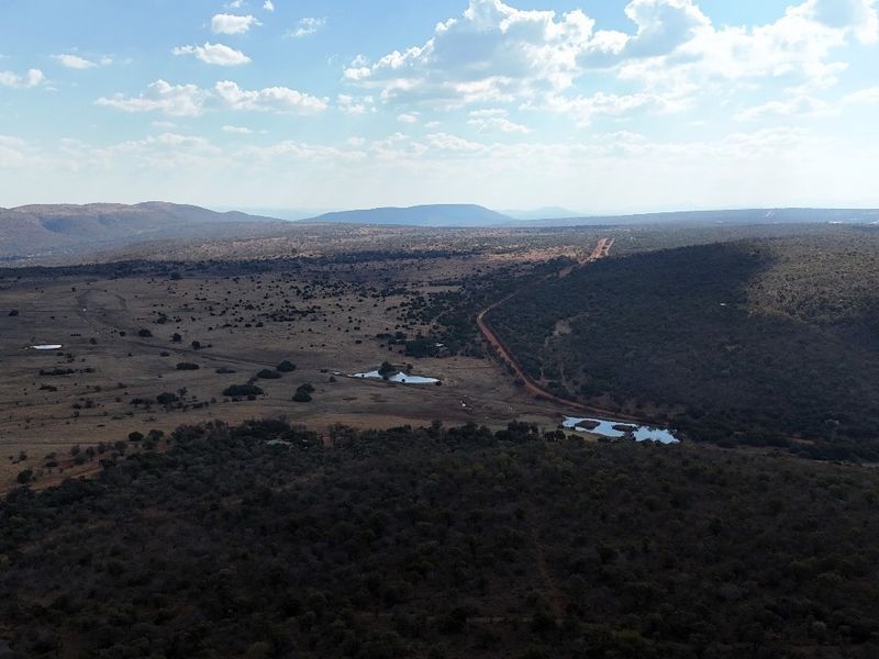 An expansive aerial view of the vacant residential land, showcasing the natural topography, vegetation, and existing water features on the property.