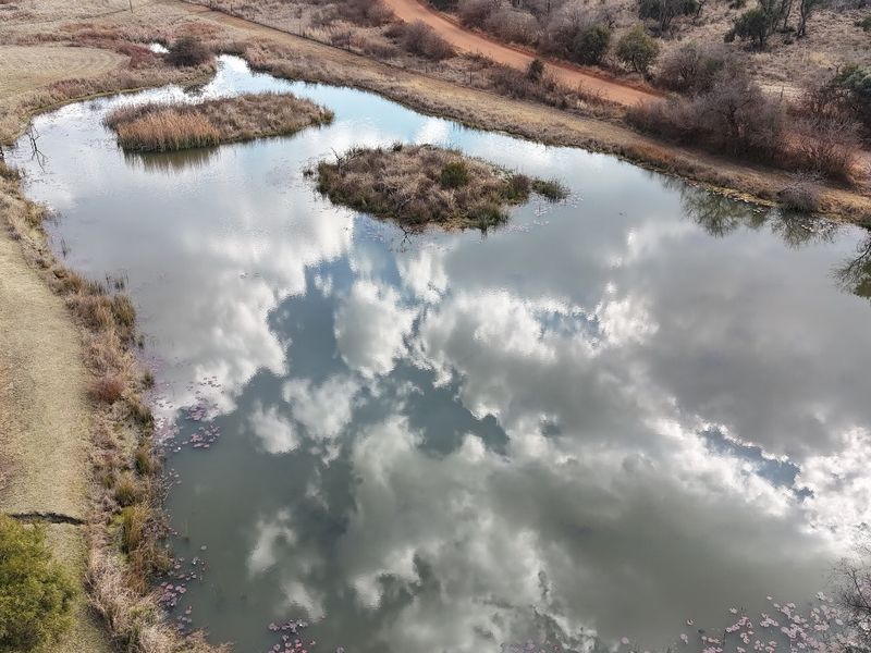 Aerial view of a natural dam on the property, featuring small islands and a nearby dirt road access.