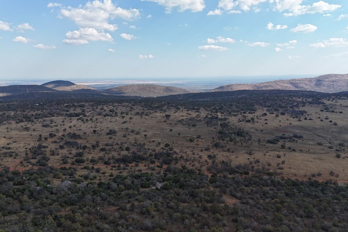 An expansive aerial view of the vacant residential land, showcasing the natural landscape, surrounding vegetation, and distant mountain ranges.